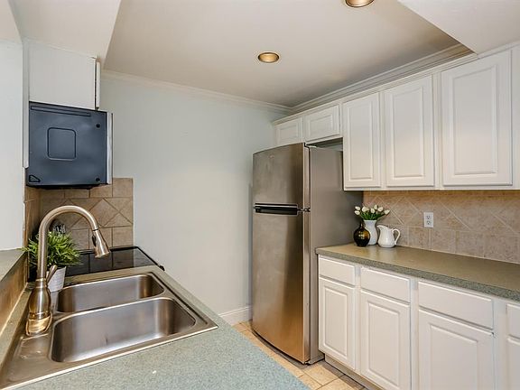 The kitchen has recessed lighting, white cabinets and stainless steel appliances. The seller is leaving the refrigerator.