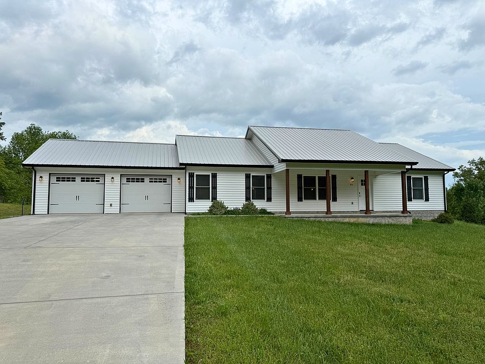 Front exterior of home with large driveway, 2 car garage, and front deck