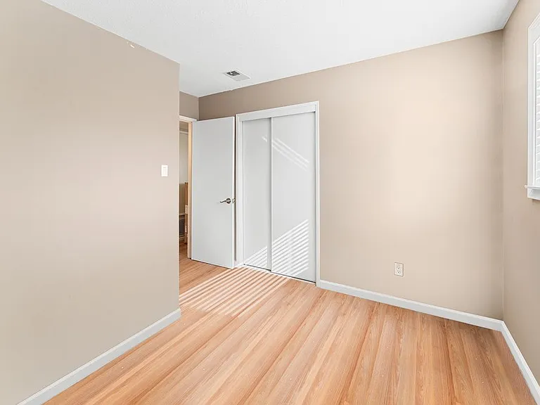 First bedroom featuring new hardwood floors, fresh paint, updated blinds, and a built in closet.