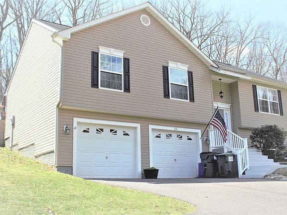 Side view closer up to highlight garbage storage, rockbed lining the driveway and newly painted porch/staircase
