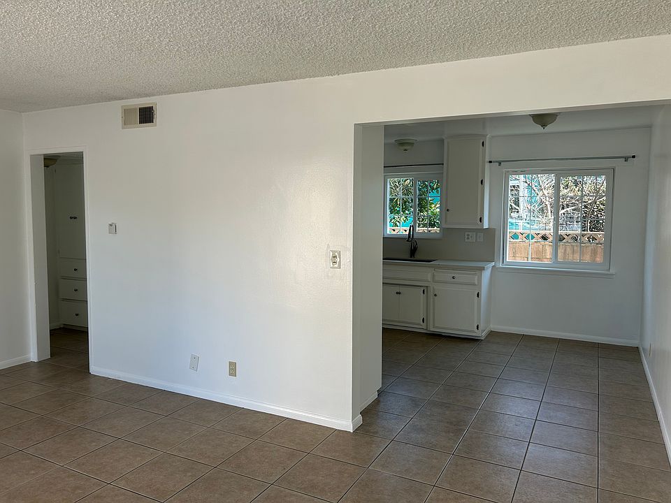 Living room with the kitchen on the right and small hallway and storage on the left