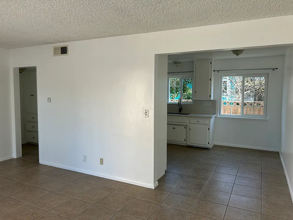 Living room with the kitchen on the right and small hallway and storage on the left