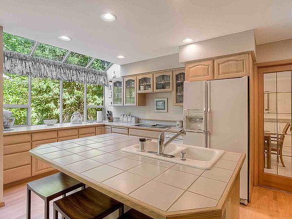 Close up view of the island showing the tile counters & the breakfast bar. To the right is the bevel