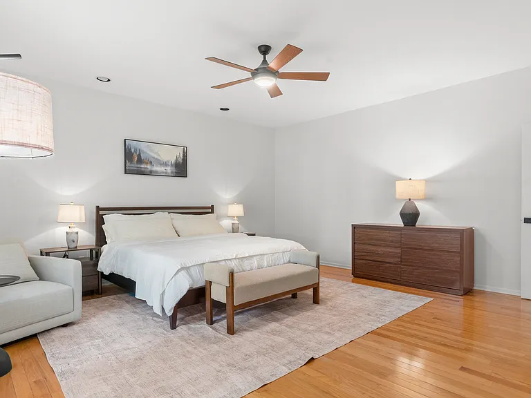 Primary bedroom with a comfortable reading chair, generous closet space, and private ensuite bathroom.
