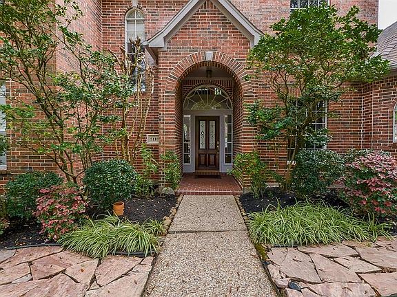 Covered front porch with leaded glass front door. Transom and side lights allow natural lighting to flood the foyer. Brick front porch is welcoming to guests and family. Stone walkways surround the pretty garden. Sprinkler system a plus.