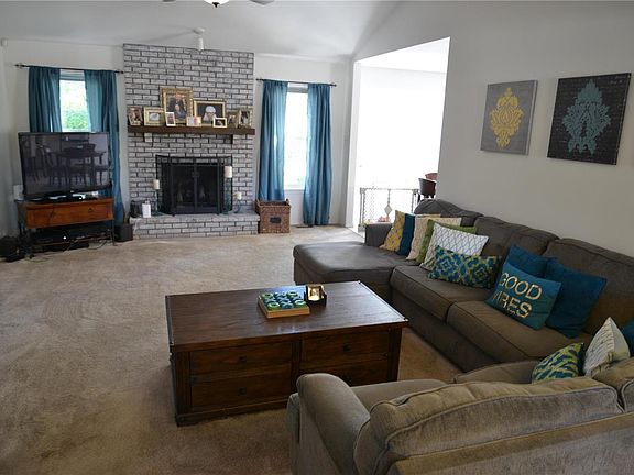 Large family room with vaulted ceiling, fan/light, gas fireplace and large windows.