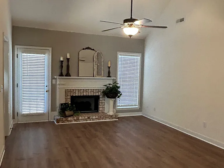 Beautiful living room with ceiling fan and accent wall featuring brick fireplace with gas logs