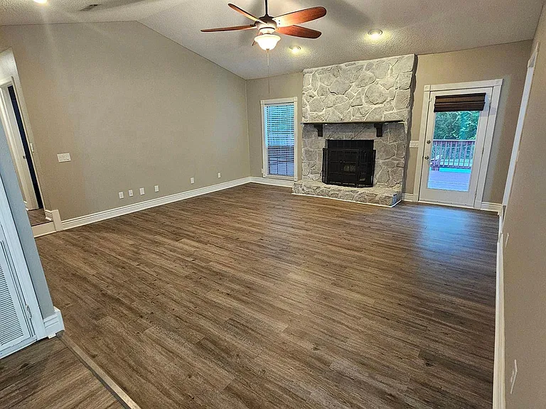 The living room with a large, updated, wood fireplace and access to the back deck. There is firewood in the back shed that can be utilized in the fireplace.