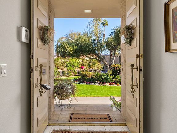 Front door with beautiful flowers and lush green grass
