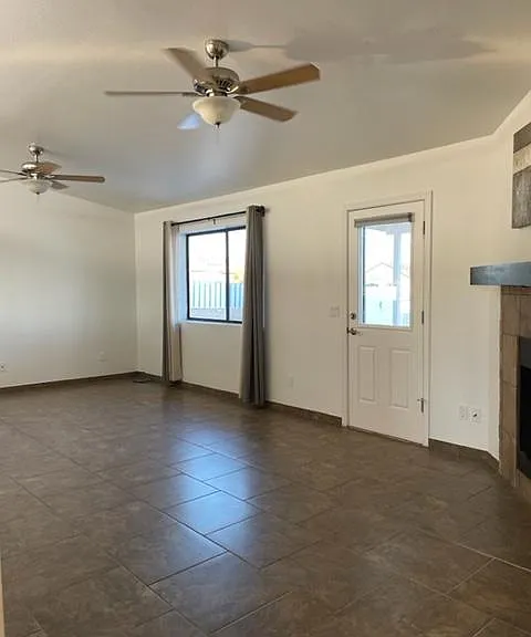Living room with vaulted ceiling, 2 fans, fireplace and door with security screen to backyard offering amazing cross breeze