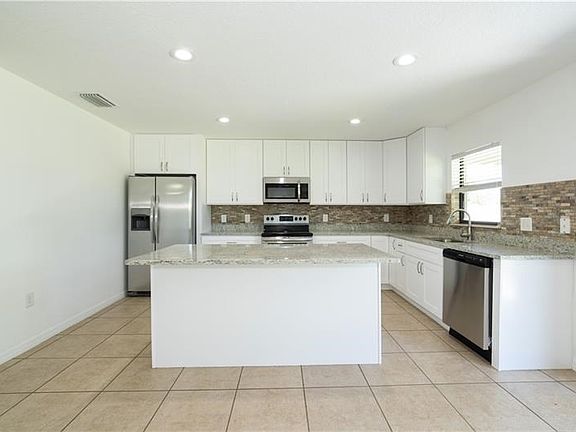 Beautiful new kitchen with island, granite stone back-splash and Stainless Steel appliances