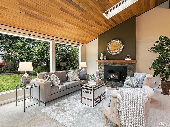 Living room with gorgeous vaulted ceilings and sky lights.  Notice the wall of windows and wood-burning fireplace!