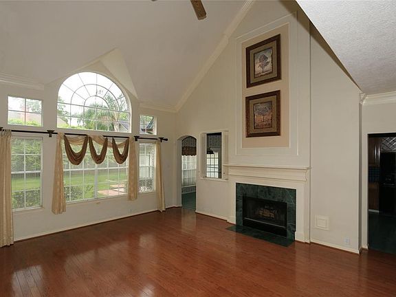 The huge living area has soaring ceilings, a wall of windows, recessed lighting, ceiling fan,