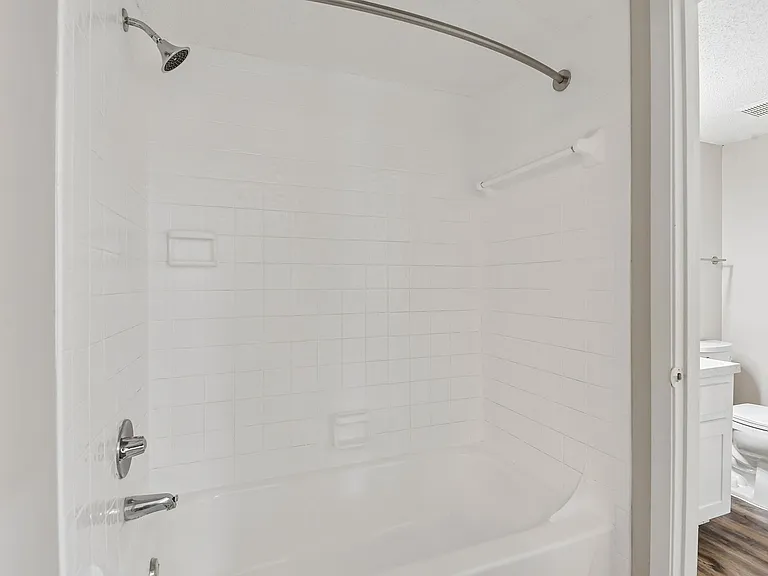 Modern bathroom with a sleek white tiled bathtub and elegant fixtures, ideal for relaxation.