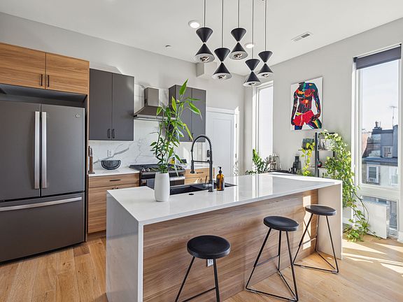 Custom kitchen with marble tiled backsplash, GE appliances, quartz countertops and waterfall island.