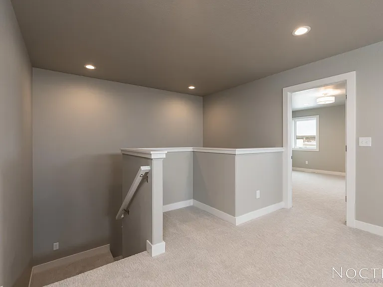 Stairs leading to a bonus room. Doorway leads to master bedroom. (Photo of another unit with similar finishes and quality.)