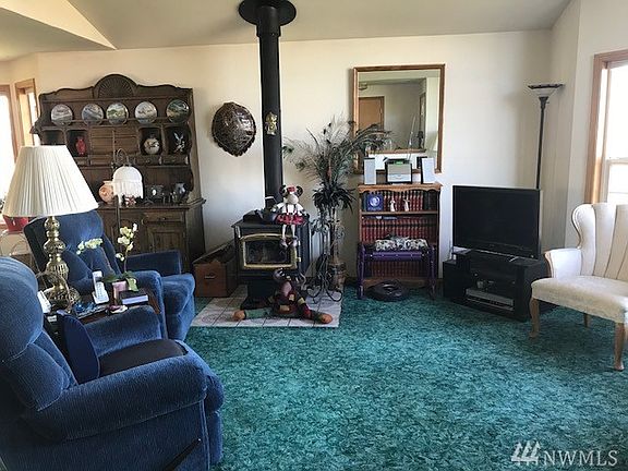 Living room with vaulted ceiling, central wood stove and bay window facing the view of the Strait.