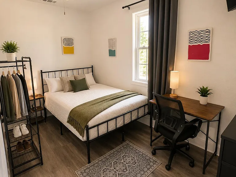 Furnished bedroom with a full bed, work desk, ceiling fan, and window with curtains for comfortable daily living.