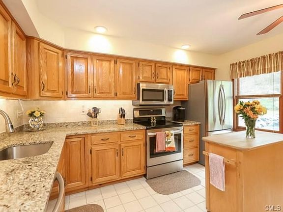 Light and bright kitchen with ceiling fan and tile floor.
