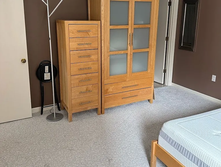 Spacious primary bedroom with high-end bed frame, dressers, and natural light.