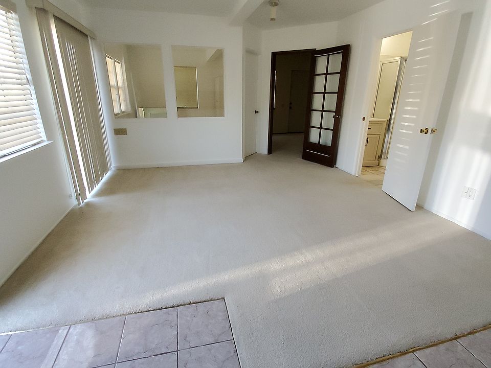 Full view of living area with two rear bedrooms and bathroom to the right. tiled floor in front of kitchenet area.