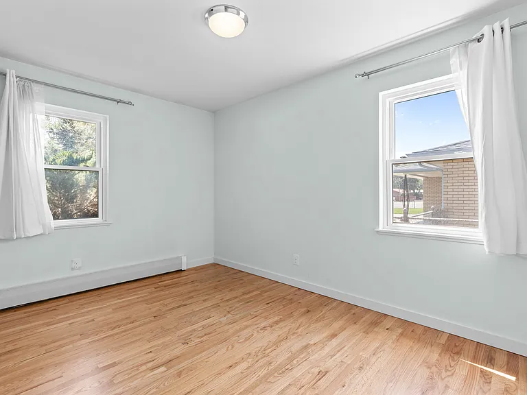 Natural light from two windows makes the third bedroom feel bright and welcoming.