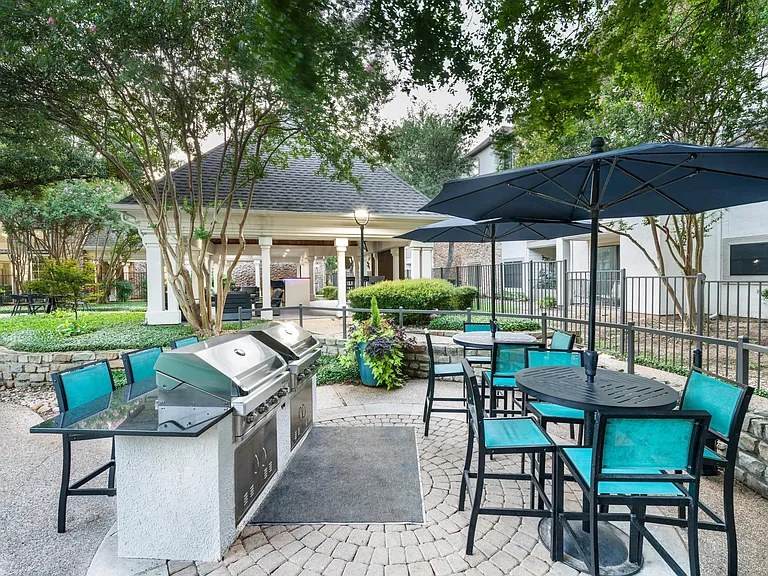 Grill and gather in the shaded outdoor kitchen, featuring built-in gas grills, bar seating, and space to enjoy a meal with neighbors.