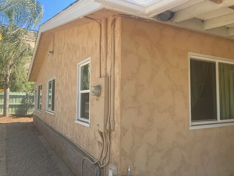 View from the back of the house towards the street. The gravel driveway is to the left of the photo. A lockable gate may be used for additional security. Two types of lights cover the driveway. One is controlled from inside the other a motion detector