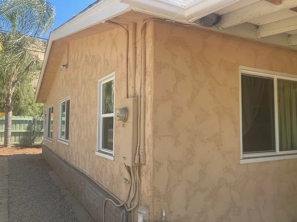 View from the back of the house towards the street. The gravel driveway is to the left of the photo. A lockable gate may be used for additional security. Two types of lights cover the driveway. One is controlled from inside the other a motion detector