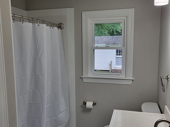 bathroom with 5 ft shower, toilet, white vanity and linen closet