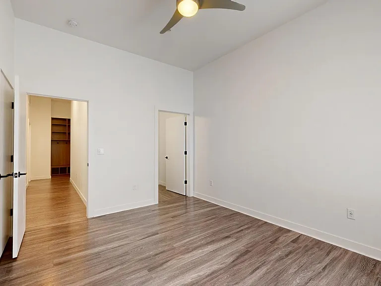 Spacious apartment bedroom with large closet and wood-style flooring.