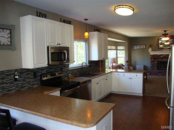 Update kitchen boasts 42" white cabinets, stainless appliances, modern tile backsplash, laminate woo