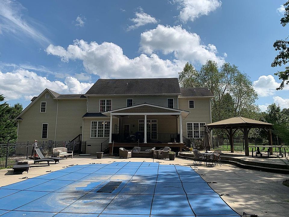 Rear of home including covered deck, patios, upper level gazebo, fenced pool