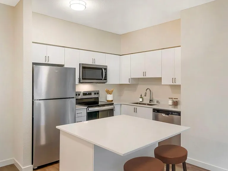 Renovated Package I kitchen with stainless steel appliances, white quartz countertops, white cabinetry, and hard surface flooring