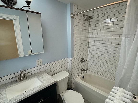 Renovated bathroom with non-slip tile floor, new vanity and shower fixtures, fresh tile, and new paint and N&S Supply fixtures.