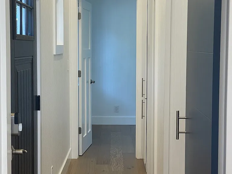 Hallway from kitchen/living room to office/den, bathroom, and bedroom at the end.
