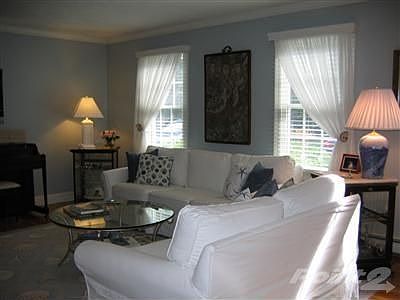 Living room with hardwood floors and crown molding. Windows are the front of home.