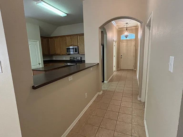 Standing in hall looking at front door and kitchen.