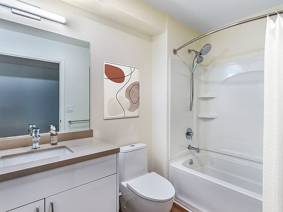 Renovated Package II bath with beige quartz countertops, white cabinetry, and hard surface flooring