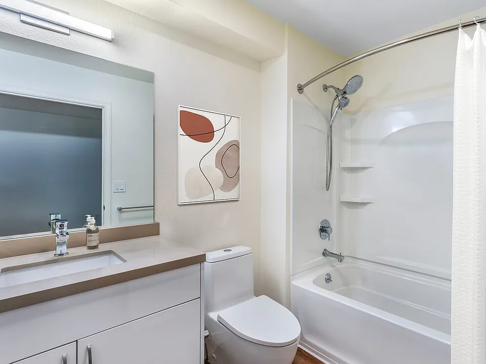Renovated Package II bath with beige quartz countertops, white cabinetry, and hard surface flooring