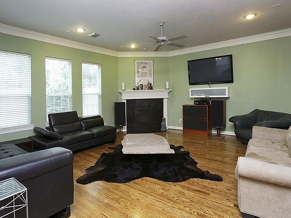 Large open living area with high ceilings, crown molding, and gas log fireplace