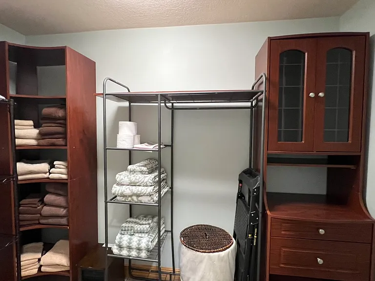 Walk-in closet. More storage and step stool for getting to those high places in the apartment. Clothes hamper. Armoire with drawers and slotted shelves for shoes or other storage needs.