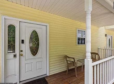 Front door and porch includes table and chairs.