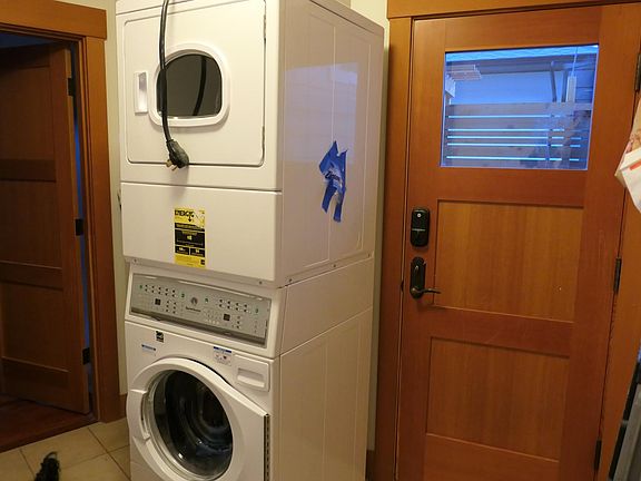 Stacking W/D assigned to tenant within mudroom. Closed door is side entrance to outdoors, easy access to parking driveway. Door has digital Yale lock.