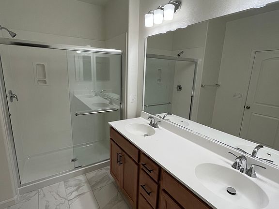 Primary bathroom with dual vanities and walk in shower