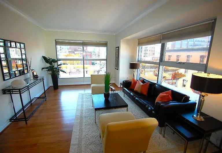 Bright Open-Concept Living Room with Large Windows and Hardwood Floors