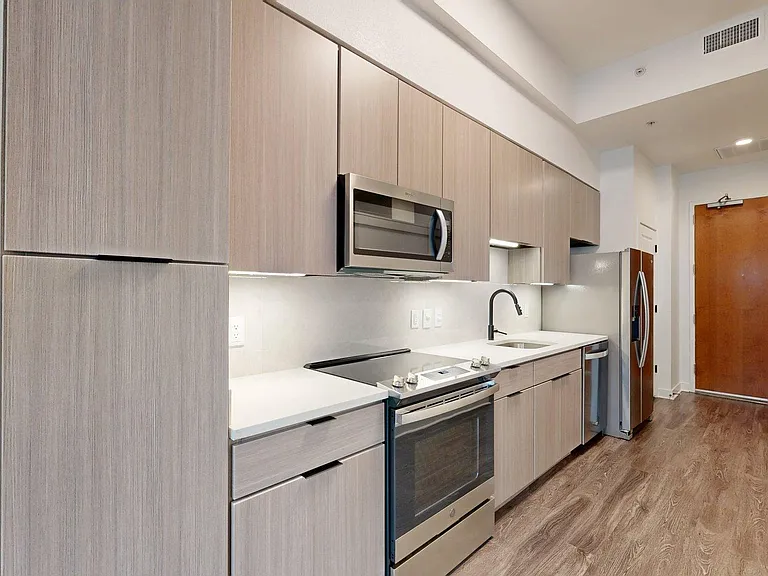 Apartment Kitchen with Quartz counter tops and Wood Style Flooring.