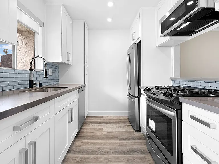 Blue tiled kitchen with stainless steel oven, fridge, dish washer, and fixtures.