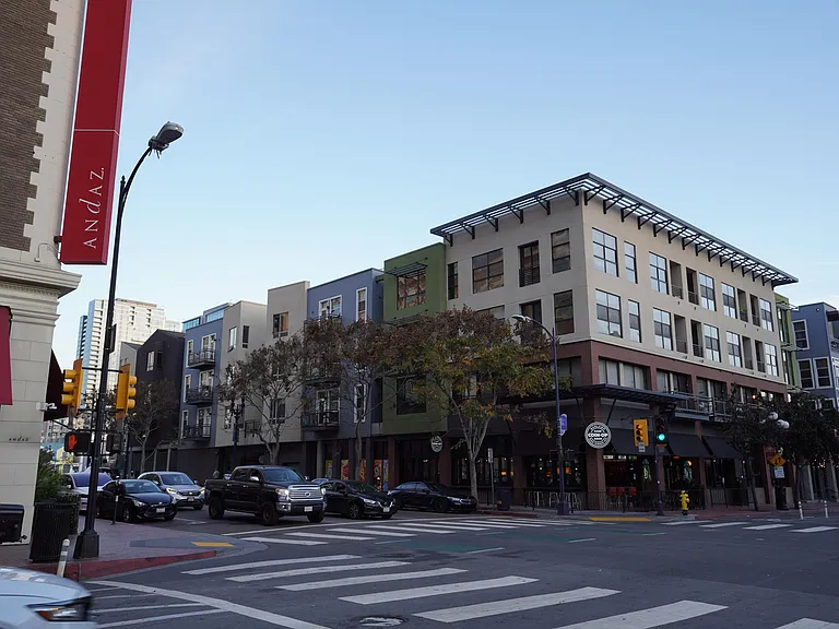 street corner of apartment building, many businesses walking distance below