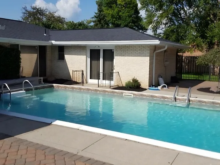 Back of home shows screen/glass sun room to left (sliding glass doors for winter room as well), windows for dining room, living room, master bath small window and walk out doors from master bedroom.